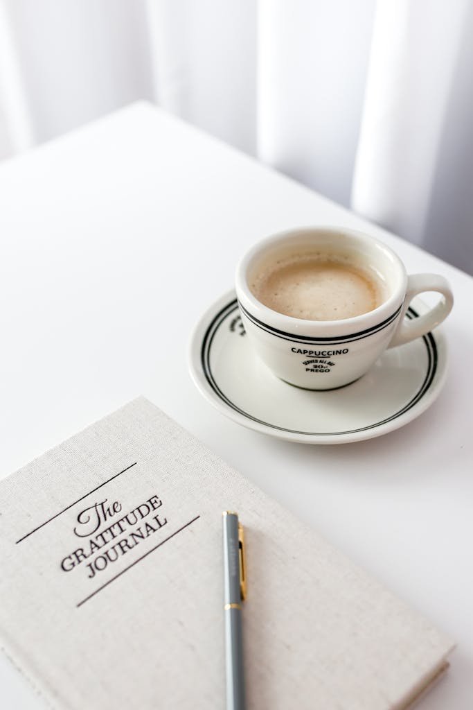 Flat lay with cappuccino and gratitude journal for a peaceful morning.